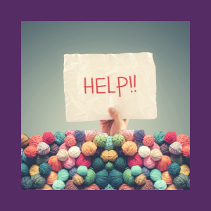 Image shows lots of balls of wool in all different colours, piled at the bottom of the photo. There is a hand coming out of the pile of wool, holding a sign that has the word 'Help' written on it.